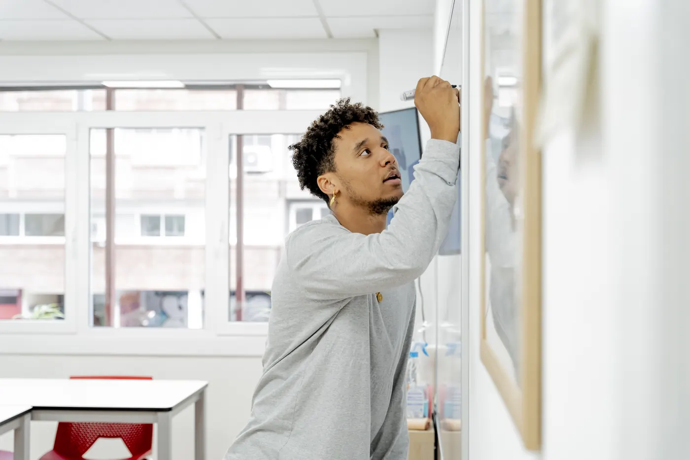 A teacher writing on a whiteboard in a classroom