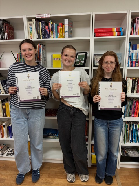 Three graduates collecting their certificates in the library